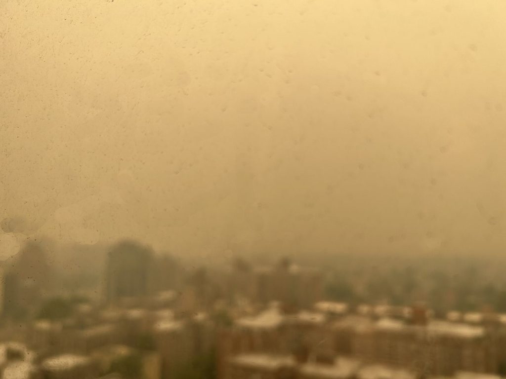 A city skyline is partly obscured by thick haze caused by air pollution.