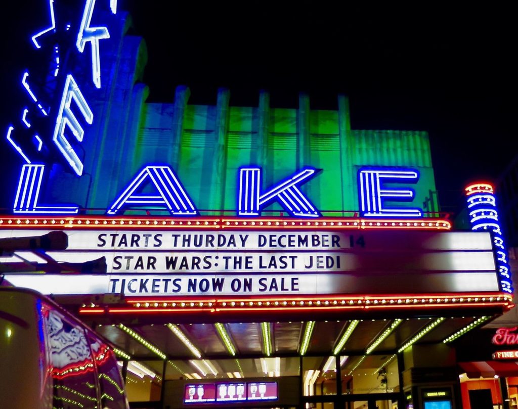 A cinema marquee lit up at night with crowds outside